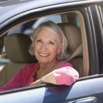 Smiling elderly woman in driver's side of the car