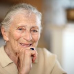 elderly lady smiling to camera with hand on chin