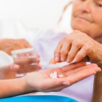 Homecare nurse helping elderly lady to take her daily medicine