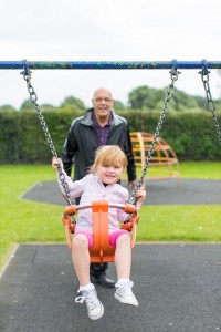 grandfather pushing grandchild on swing