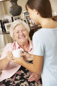 carer handing old lady mug of tea