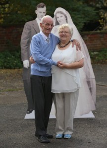 elderly couple next to cardboard cut out of wedding photograph