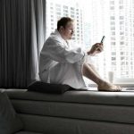 Man sitting in dressing gown looking at phone