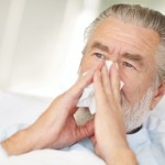 Older man sneezing into handkerchief