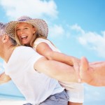 Portrait of playful mature couple having piggyback ride with arms outstretched outdoors credit Healthspan