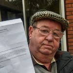 pensioner holding letter with flat cap on