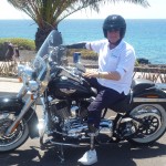 man on motorbike on seafront in front of palm tree